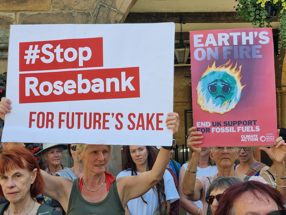 Protesters in Shrewsbury holding banners with the words "#Stop Rosebank for future's sake" and "Earth's on fire"